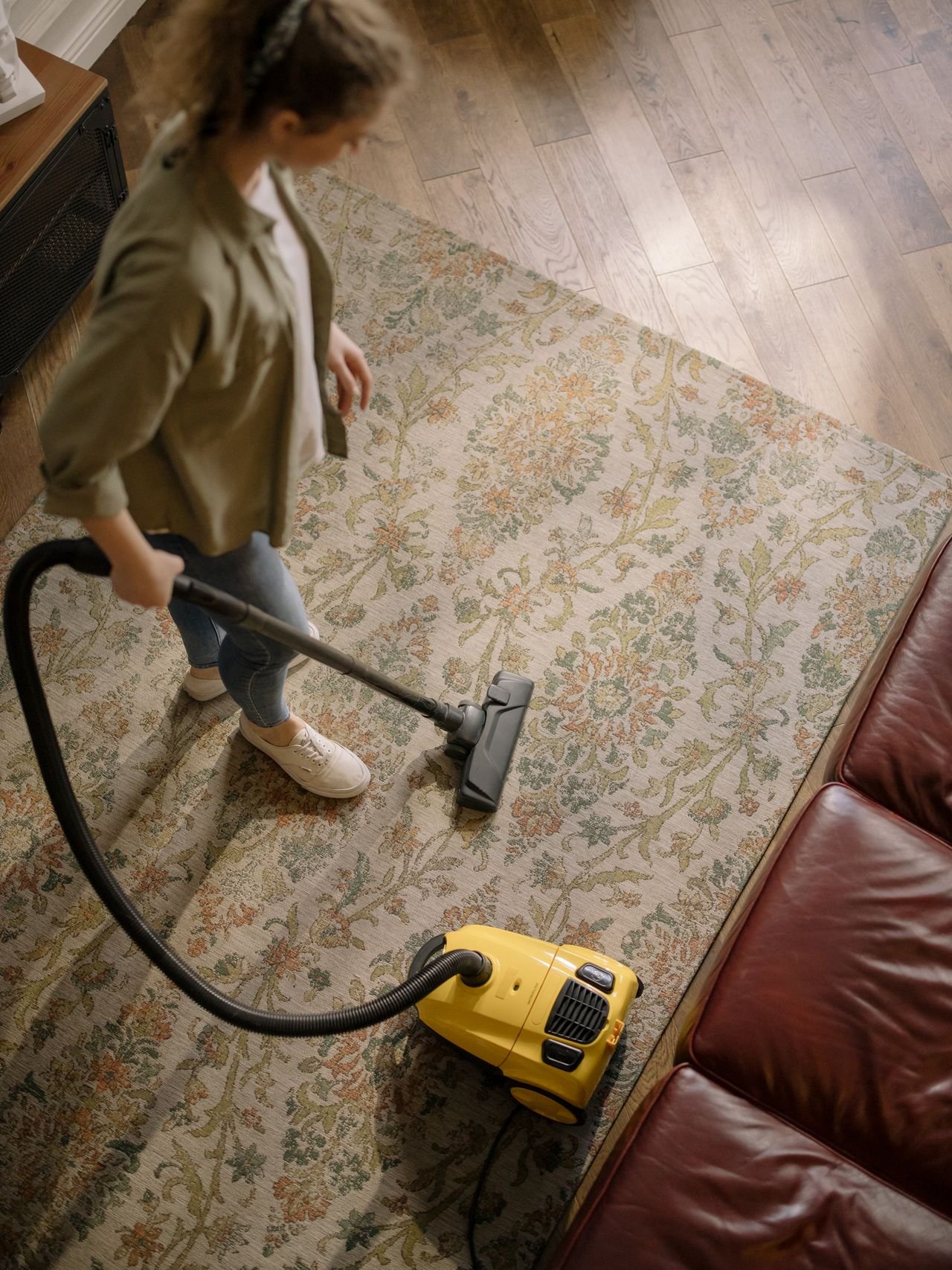 Cleaner vacuuming a sunlit living room
